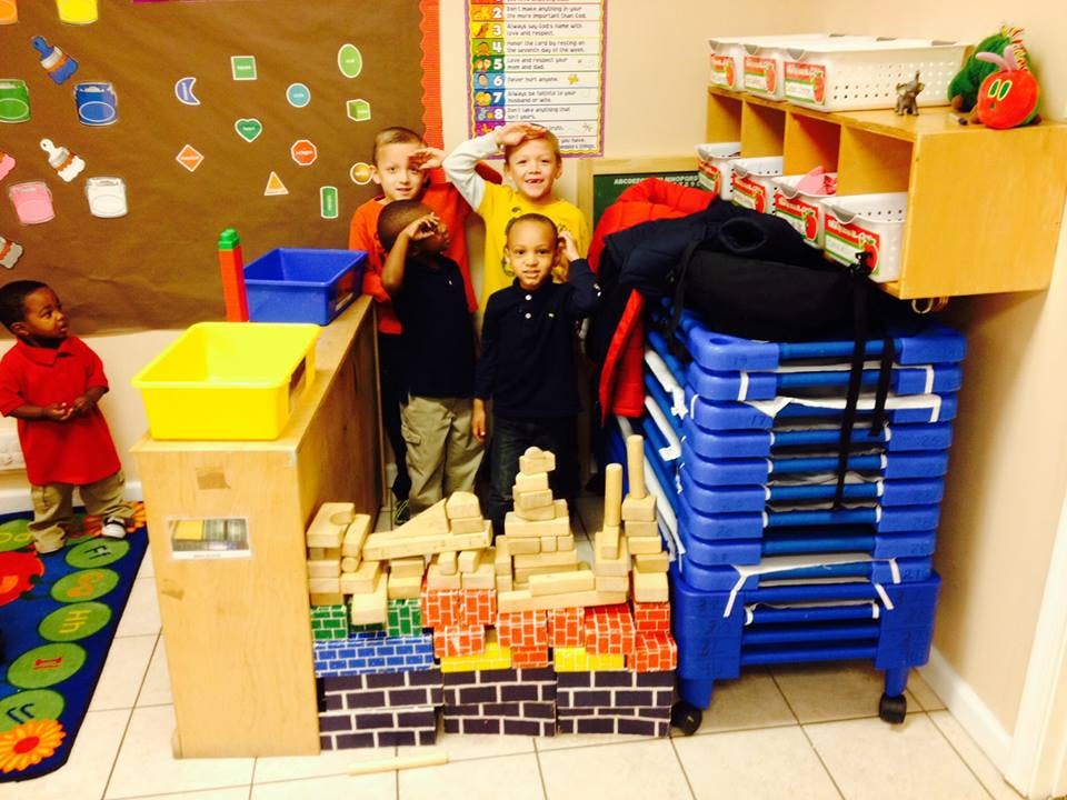 Children standing around blocks in a classroom
