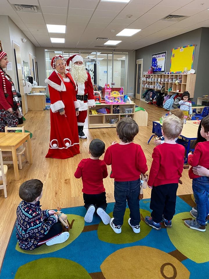 Two people dressed as Santa and Mrs Claus with children in a classroom