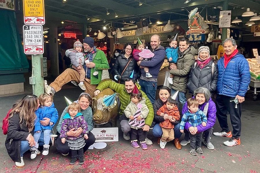 Group of people and children posing with a pig statue at Pike Place Market
