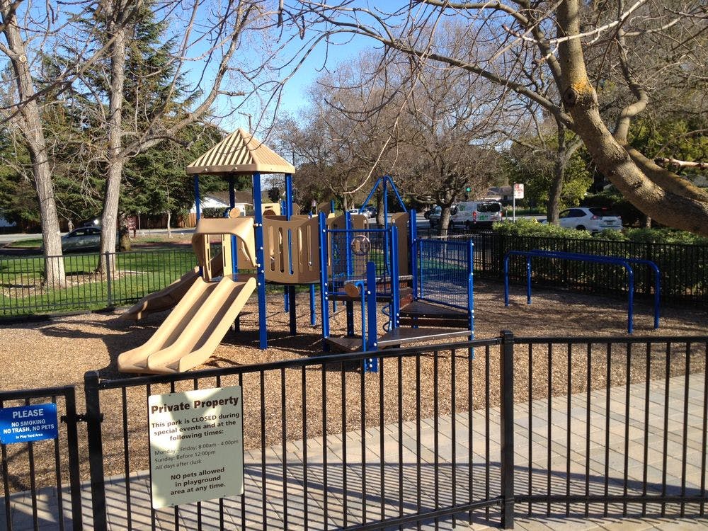 Playground with slides and climbing structures behind a fence