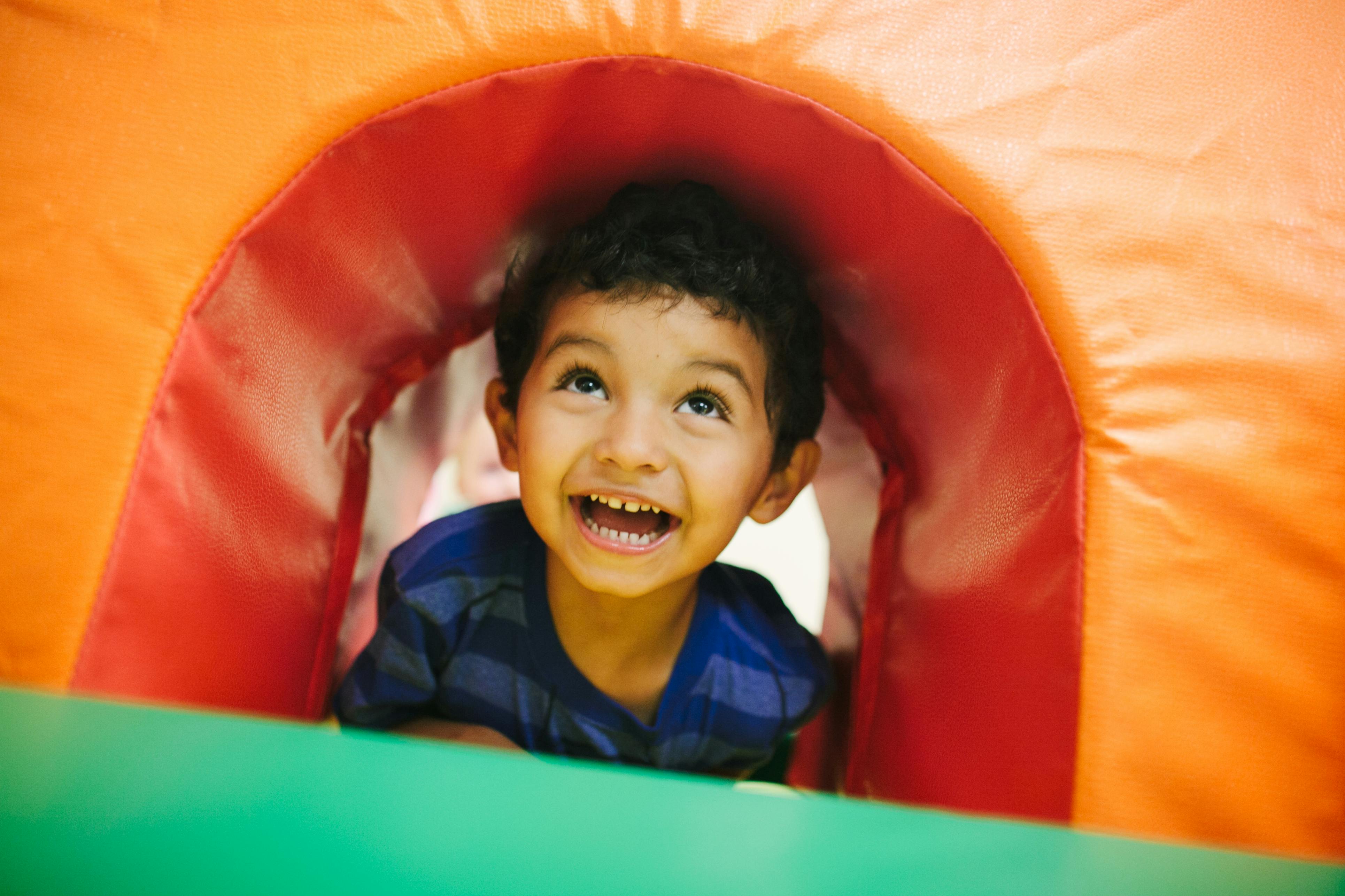 Child looking up from inside a play tunnel