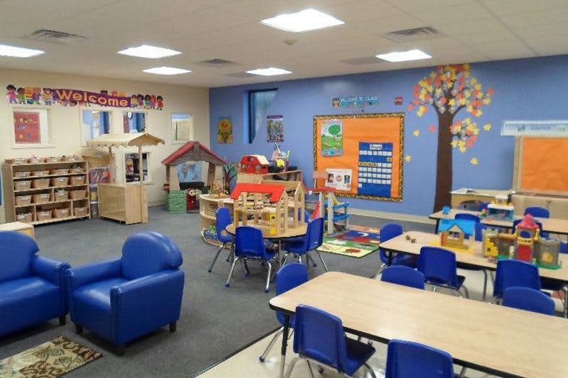 Empty classroom with small tables, chairs, and play areas