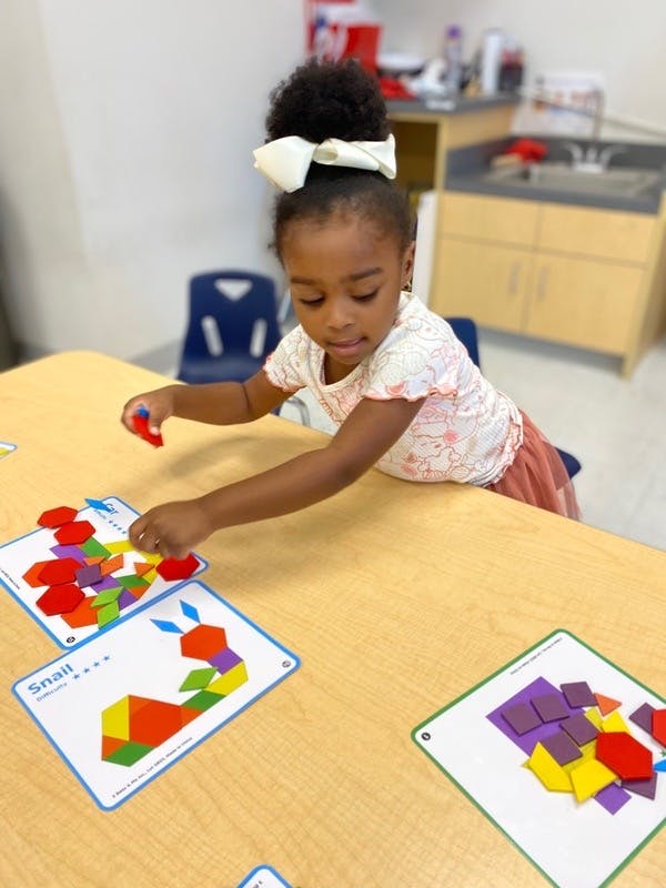 Child playing with colorful geometric shapes on a table