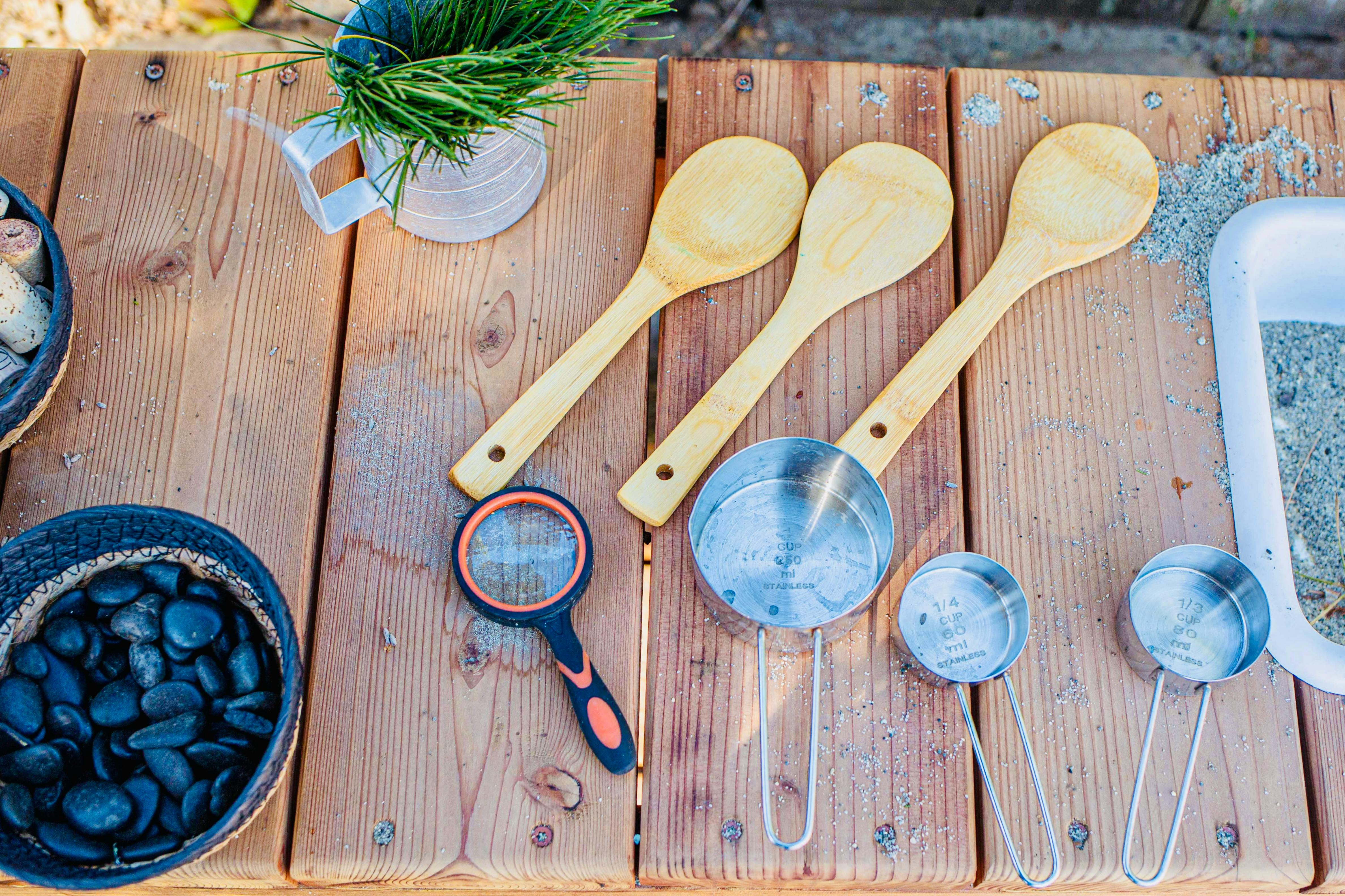 Wooden spoons, measuring cups, and a magnifying glass on a wooden table