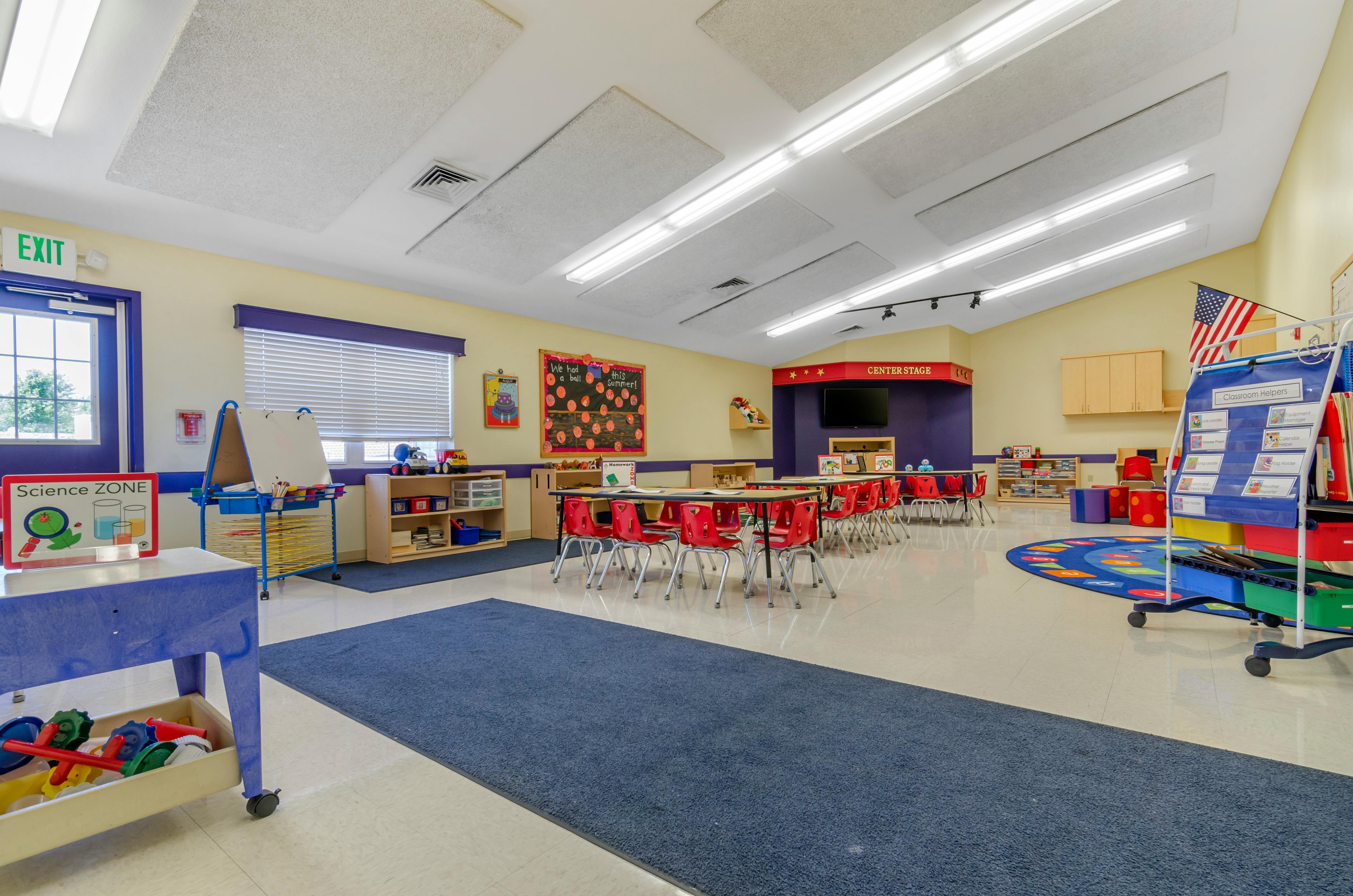 An empty early childhood classroom with colorful furniture and play areas