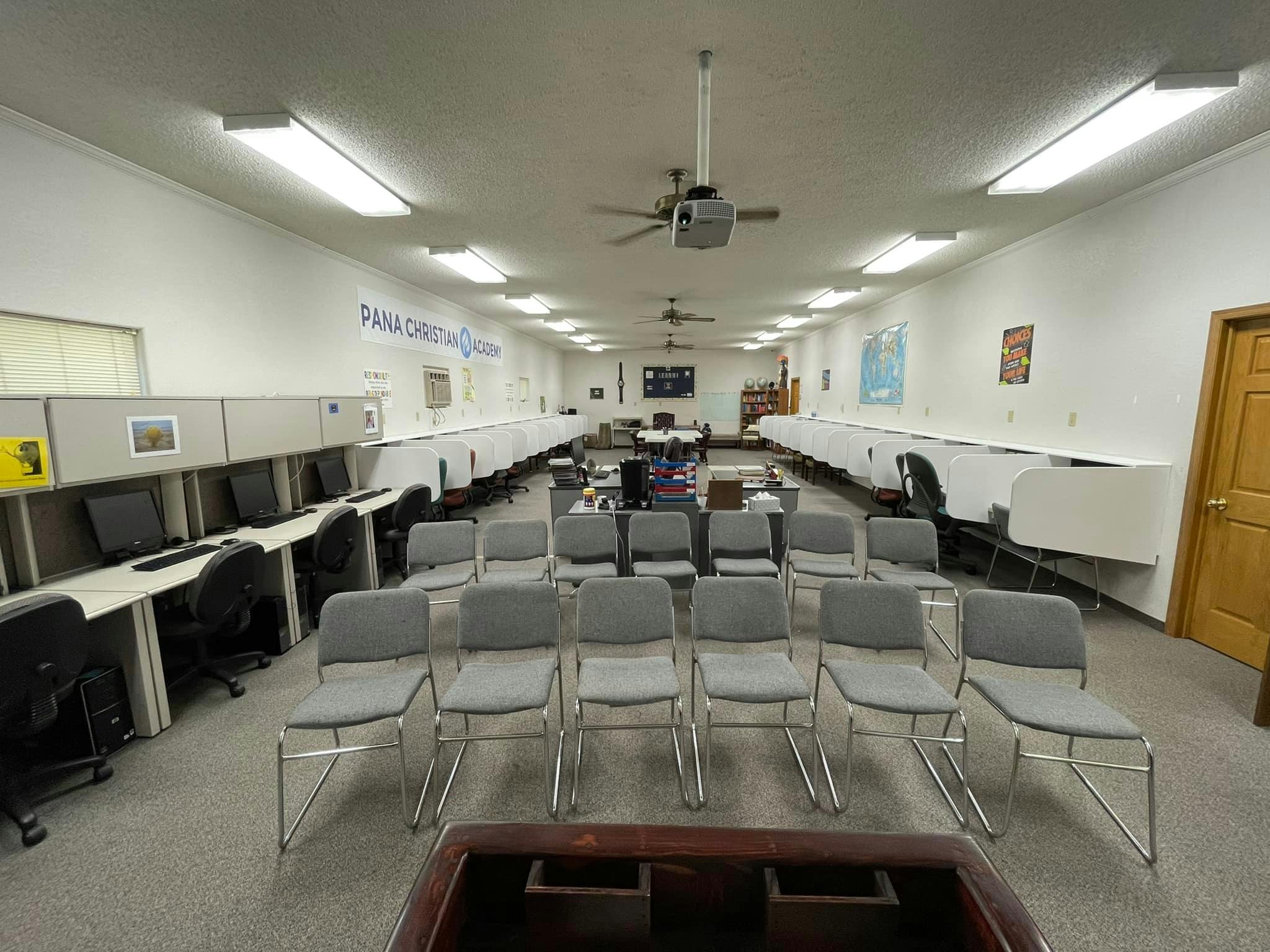 Classroom with rows of computer stations and chairs facing a central area