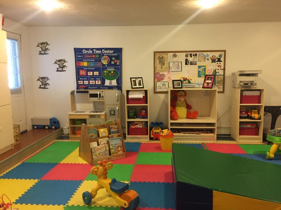 Playroom with colorful floor mats, shelves with toys, and a bulletin board