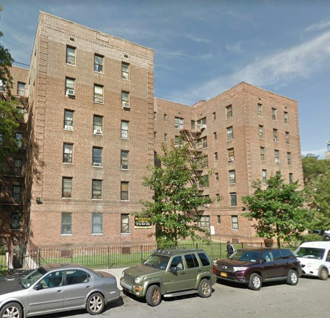 Large brick apartment building with cars parked on the street