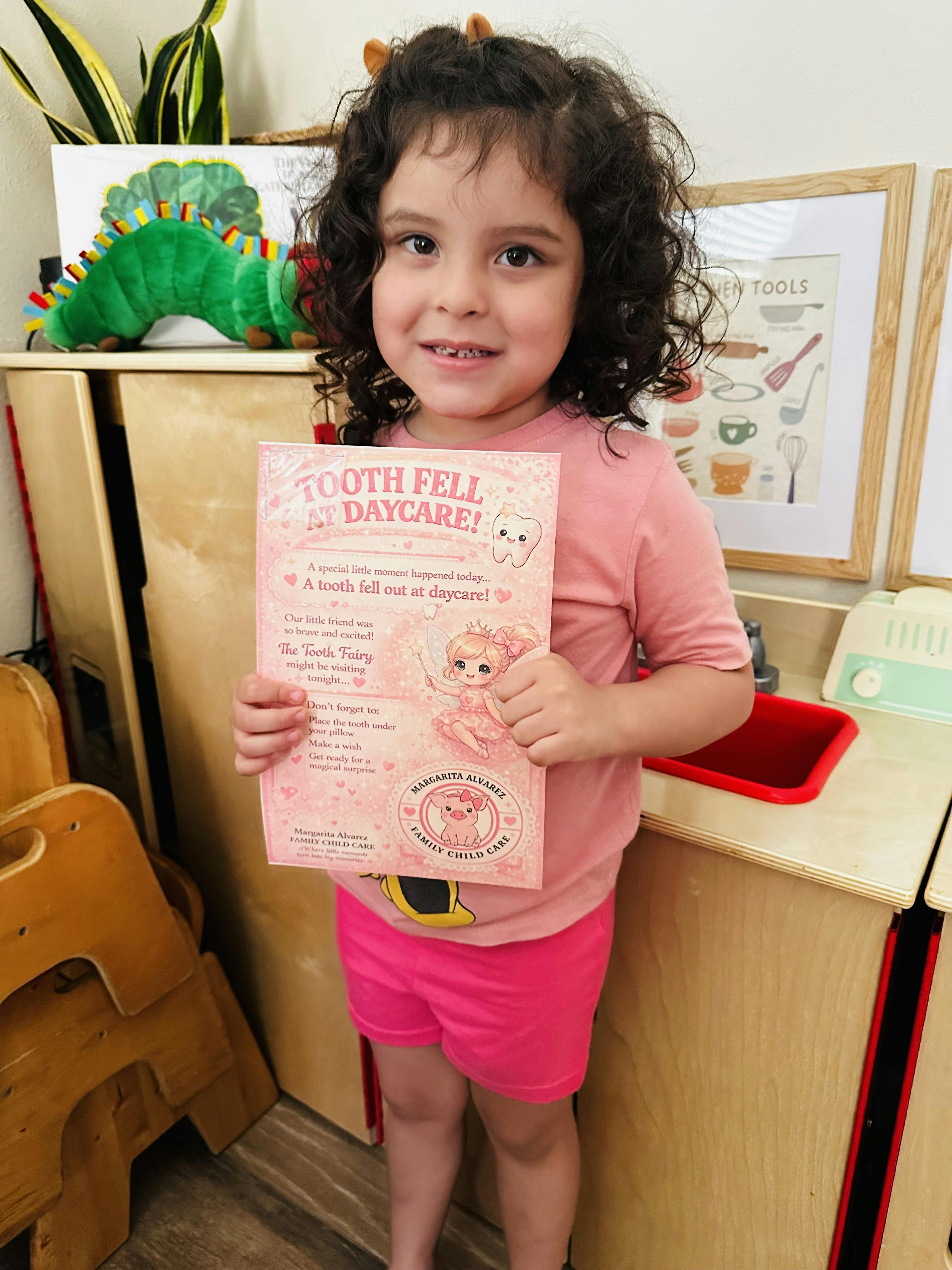 Child smiling, holding a paper that says "Tooth fell at daycare"