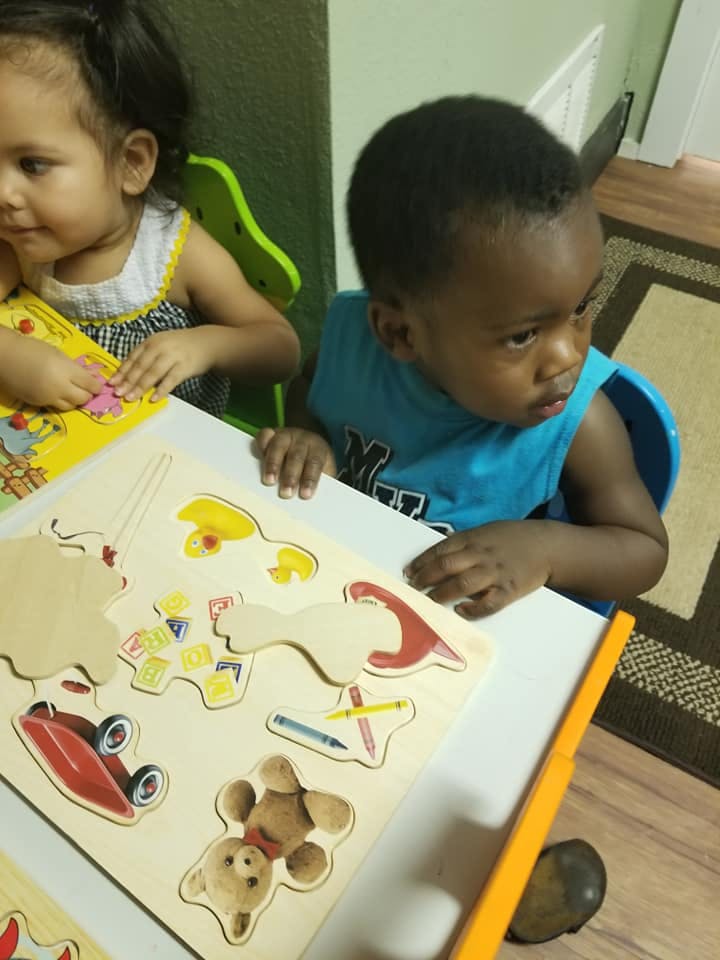 Two children playing with a wooden puzzle
