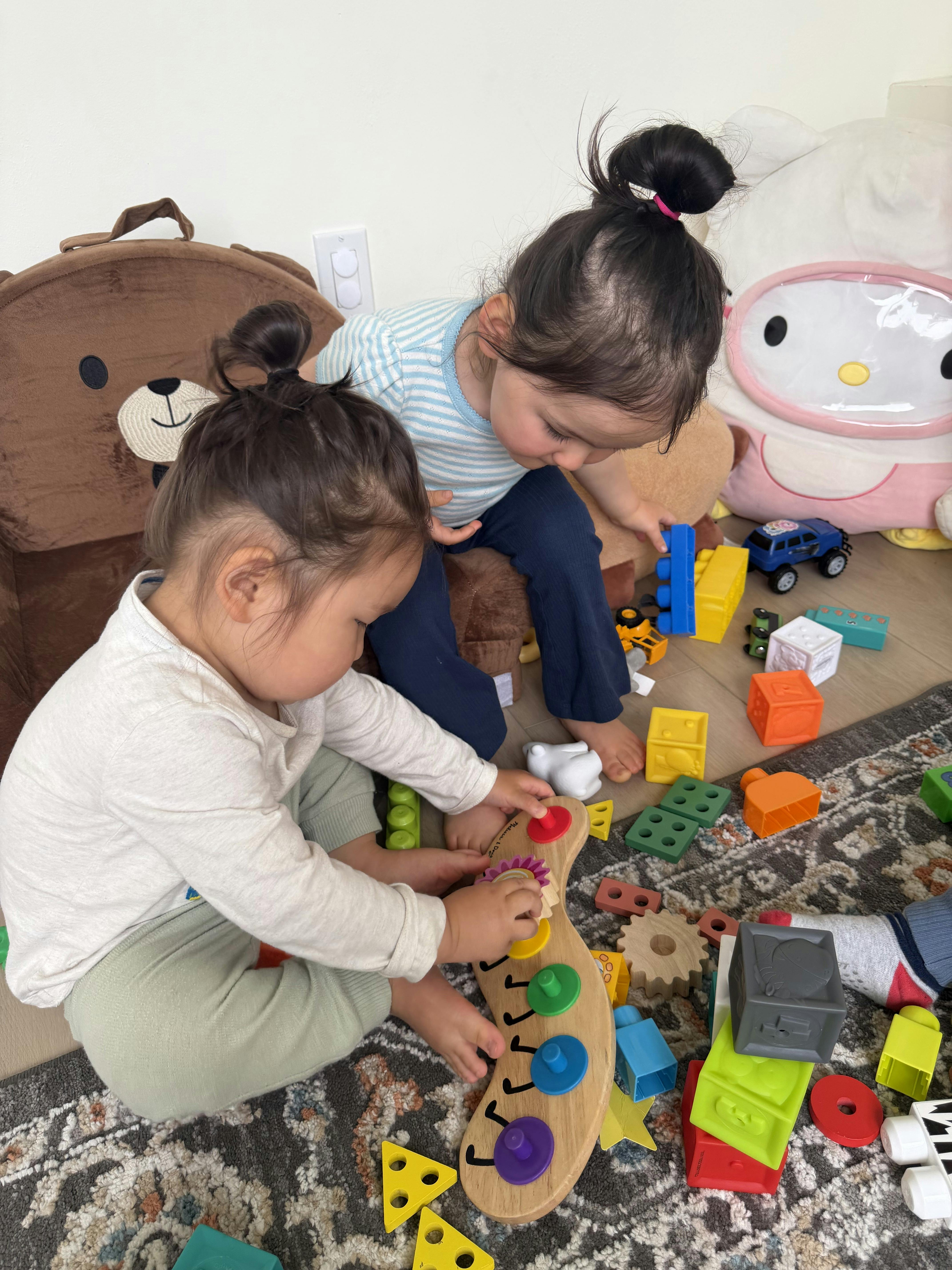 Two children playing with colorful blocks and toys on a rug