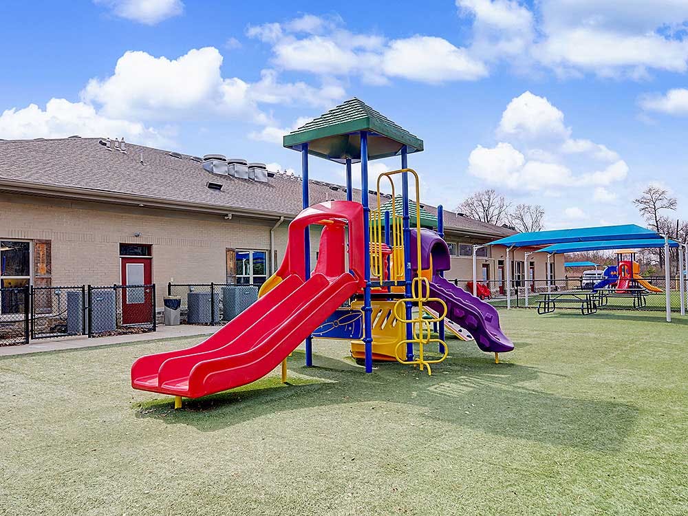 Playground with multiple slides and climbing structures on artificial turf