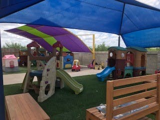 Outdoor playground with slides and playhouses under shade canopies