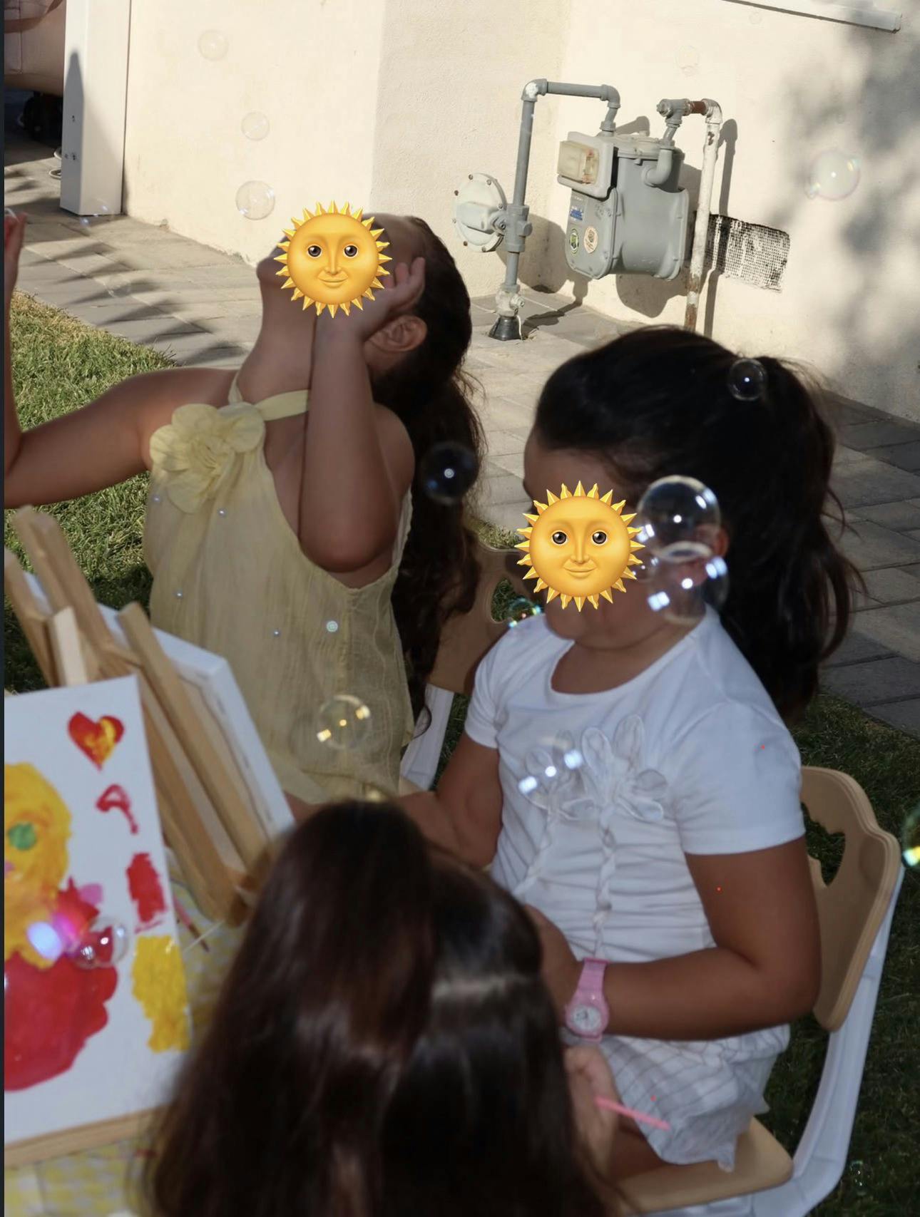 Children playing with bubbles while painting on easels outdoors