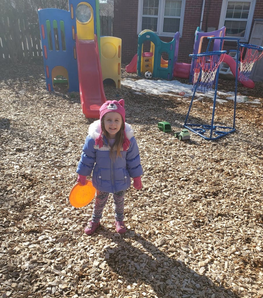 Child holding a frisbee on a wood chip playground