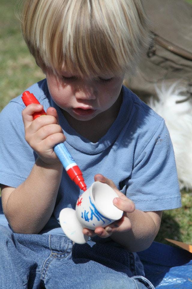 Child decorating a small cup with a marker