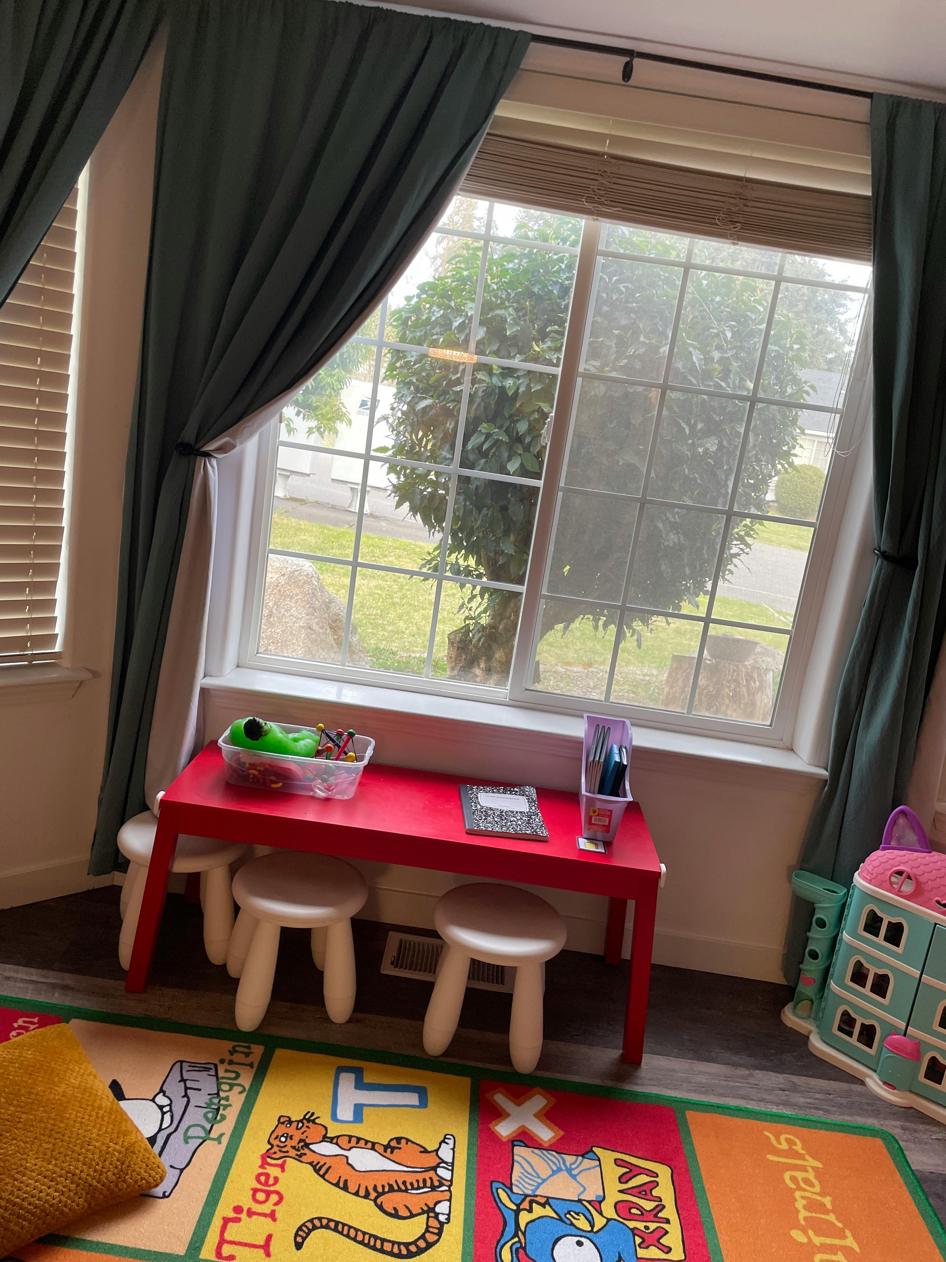 Red children's table with stools in front of a window