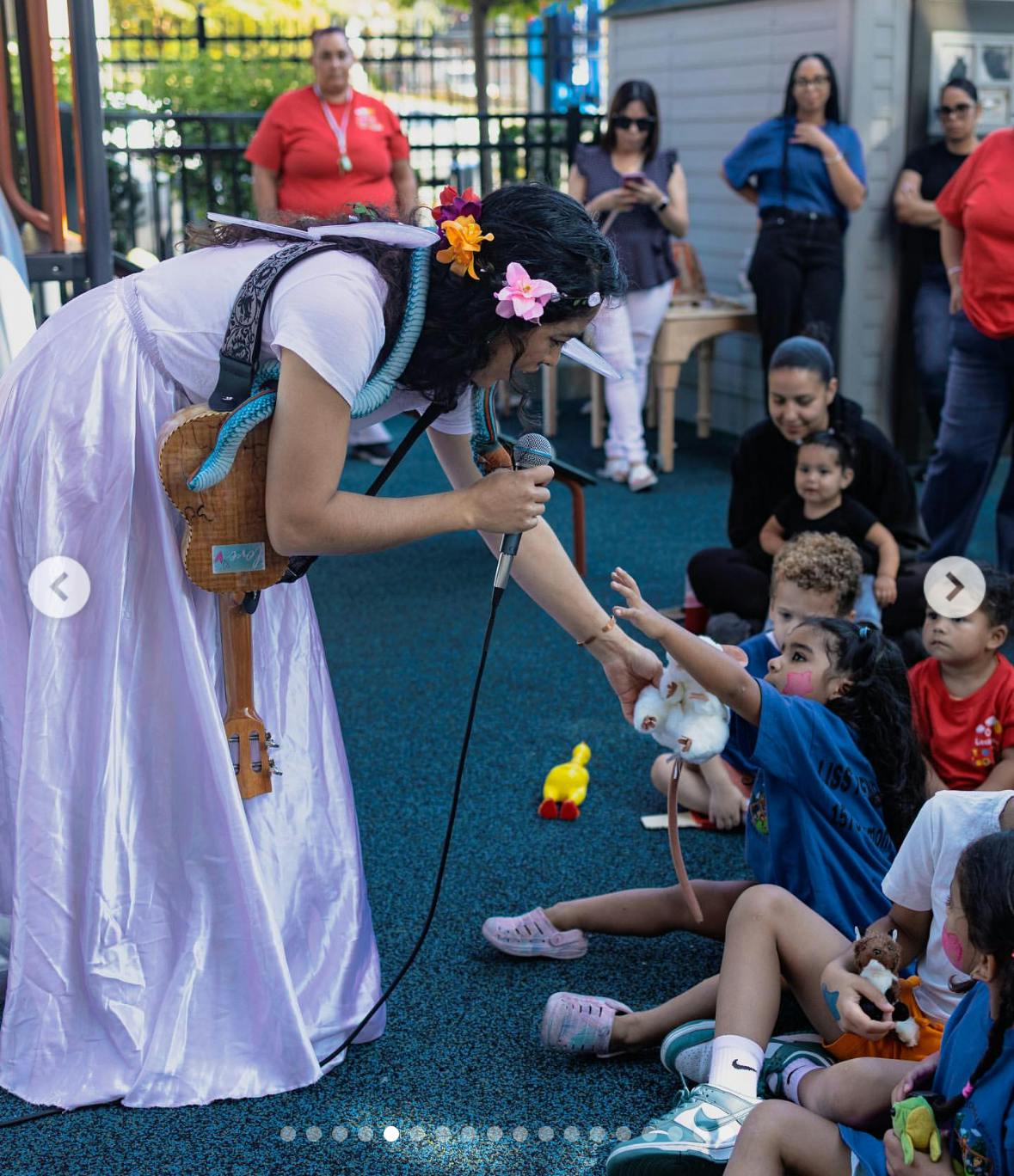 Performer in costume handing a toy to a child sitting with a group