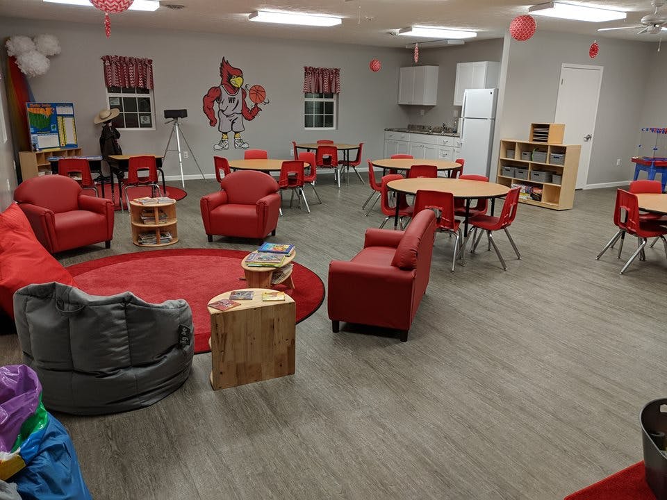 Room with red chairs, tables, and a red rug