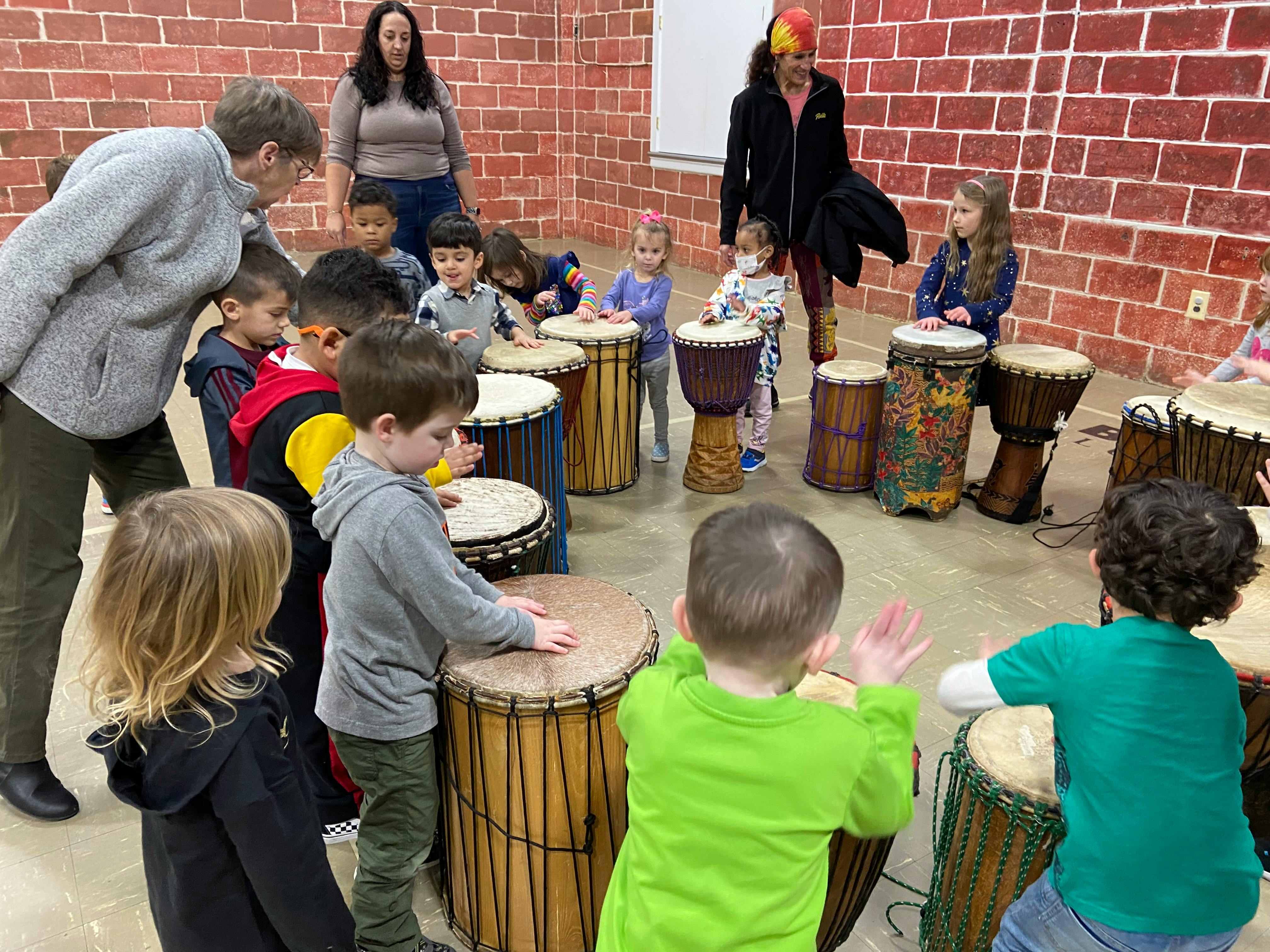 Adults and children playing drums in a room