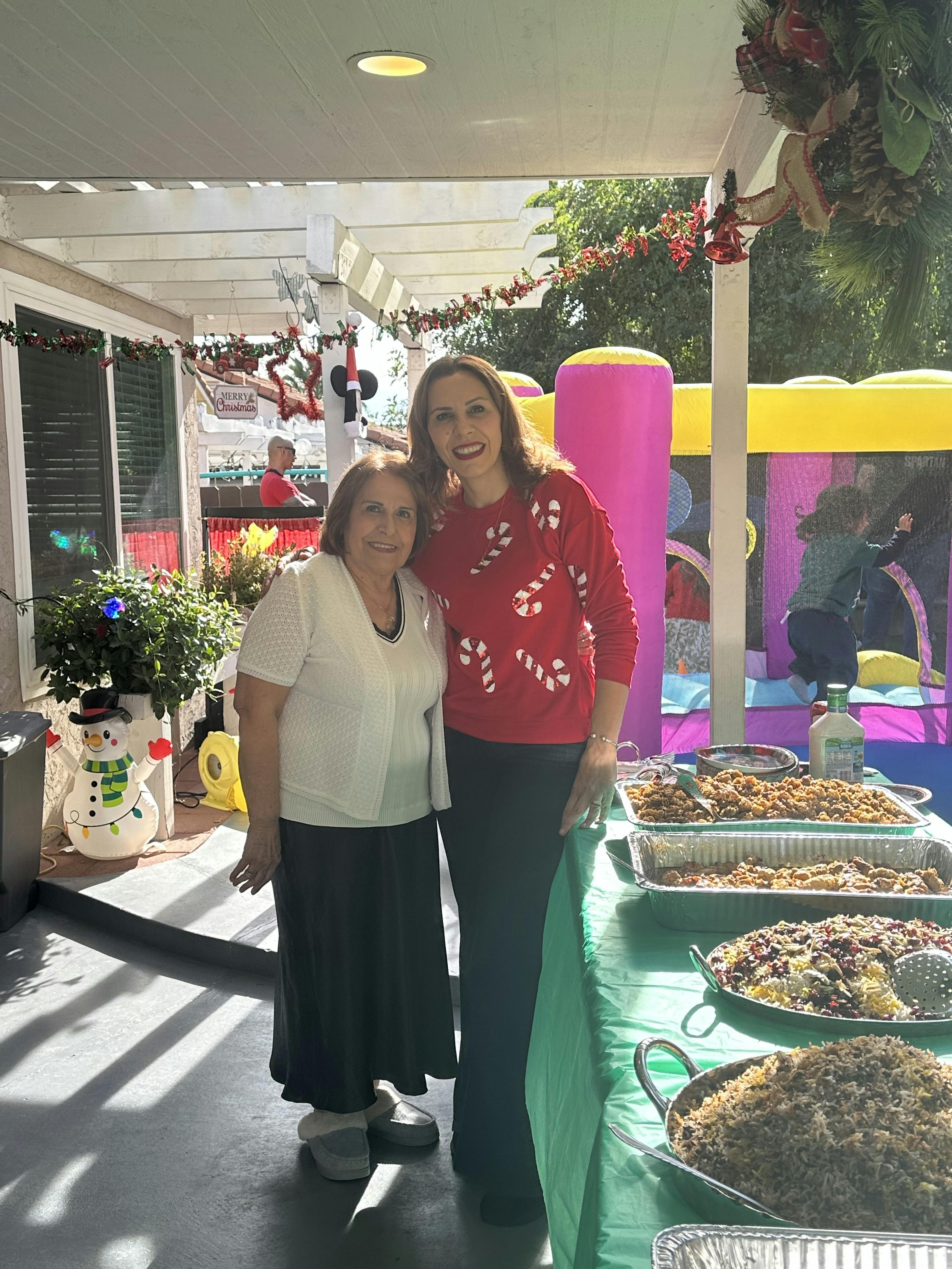 Two people standing next to a table of food with an inflatable bounce house in the background