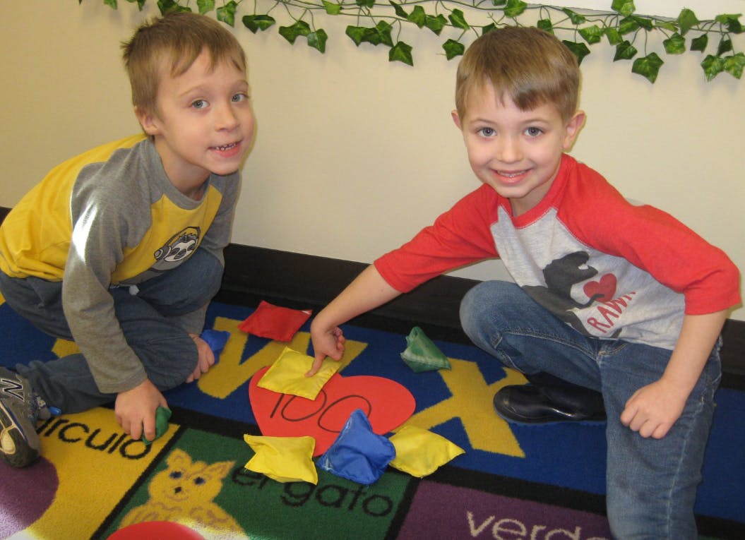 Two children playing with beanbags on a colorful rug