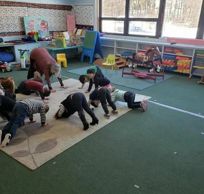 Adults and children doing yoga poses in a classroom