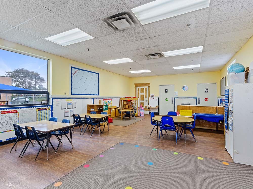 Classroom with small tables and chairs, whiteboards, and a window
