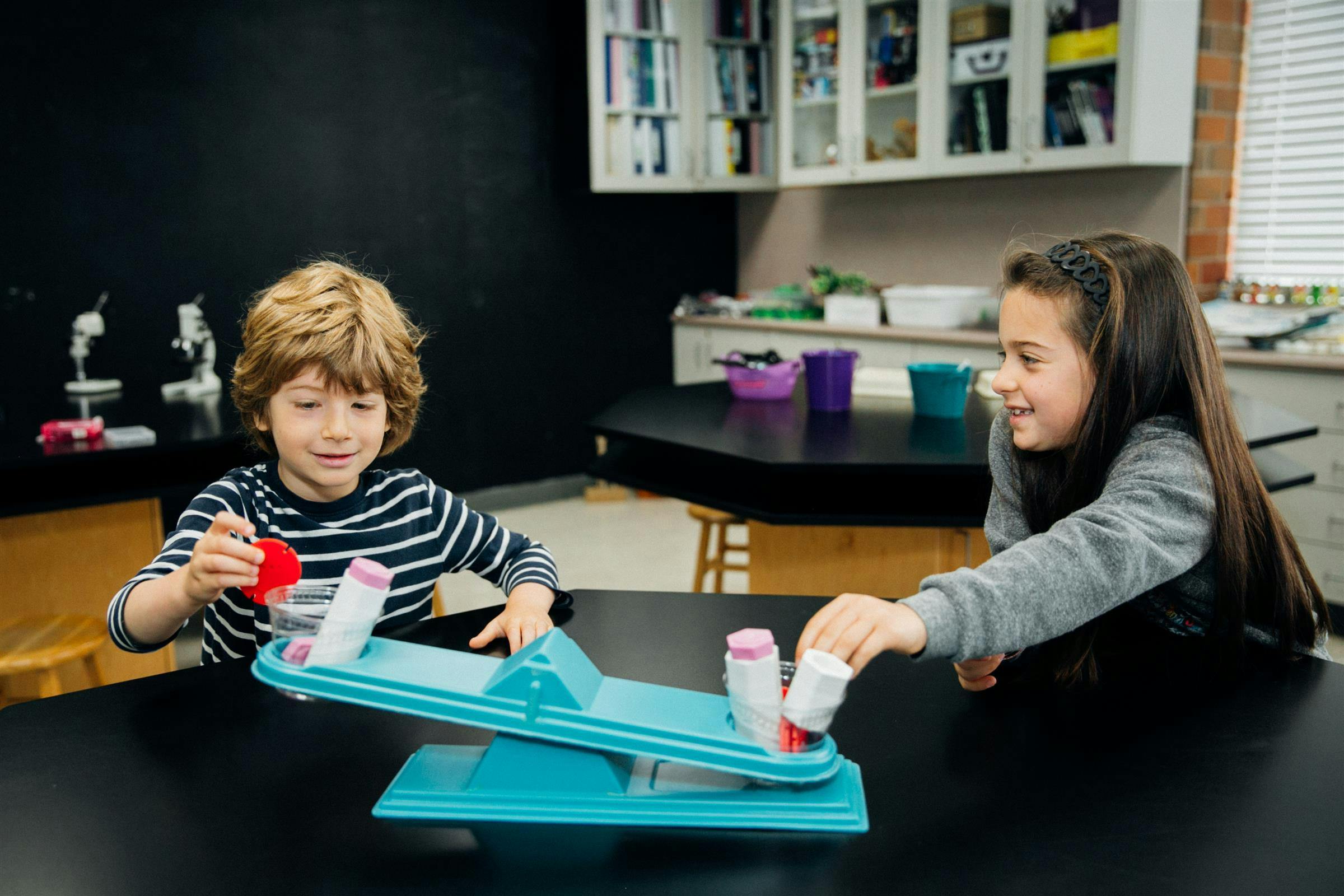 Two children playing with a balancing scale