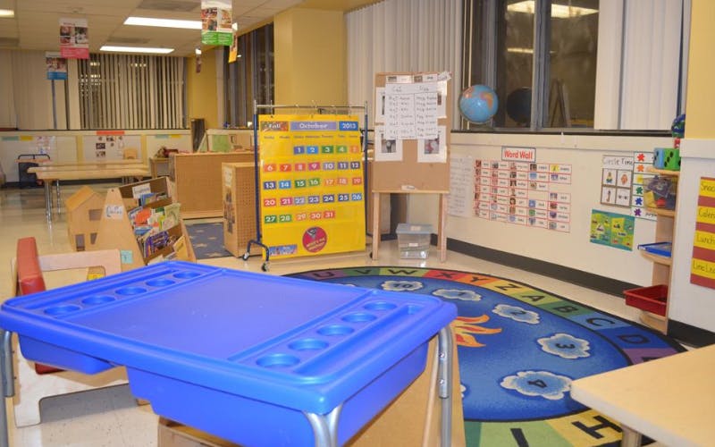 Classroom with children's furniture, an alphabet rug, and educational posters