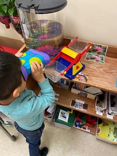 Child looking into a blue and purple toy microscope
