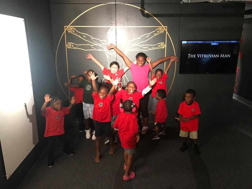 Children posing in front of a Vitruvian Man display