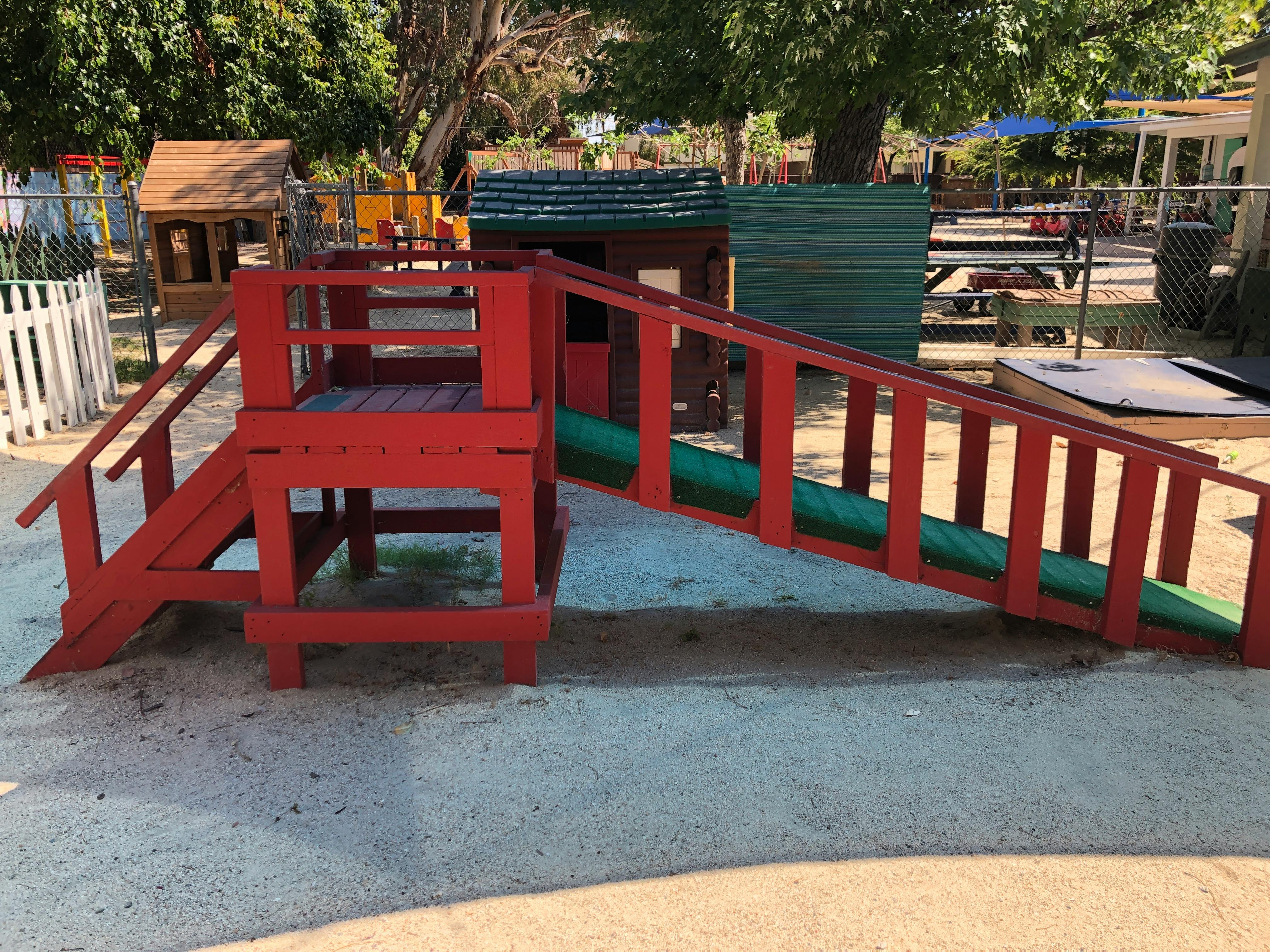 Red wooden playground structure with a green slide