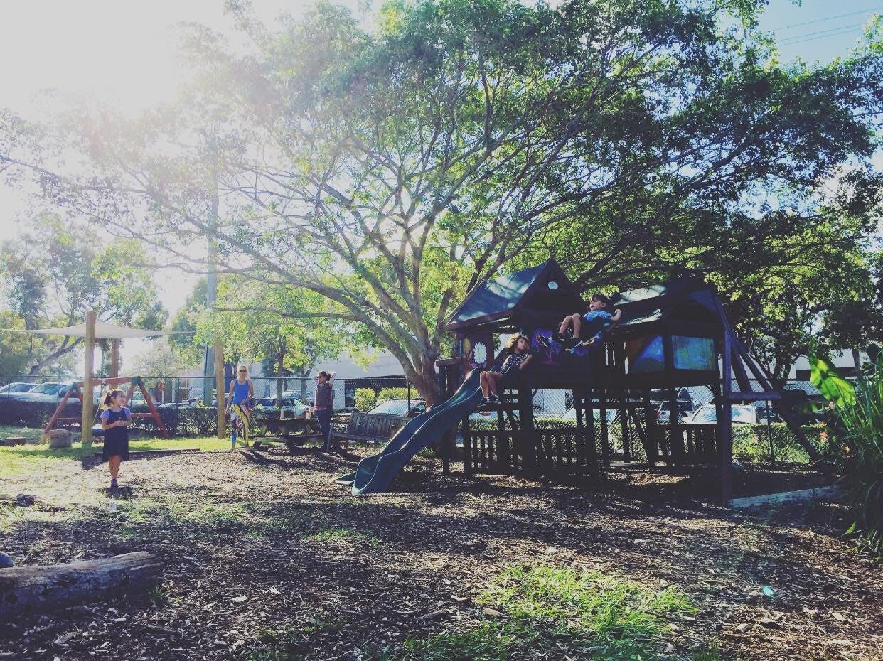 Children playing on a playground with a slide and climbing structure