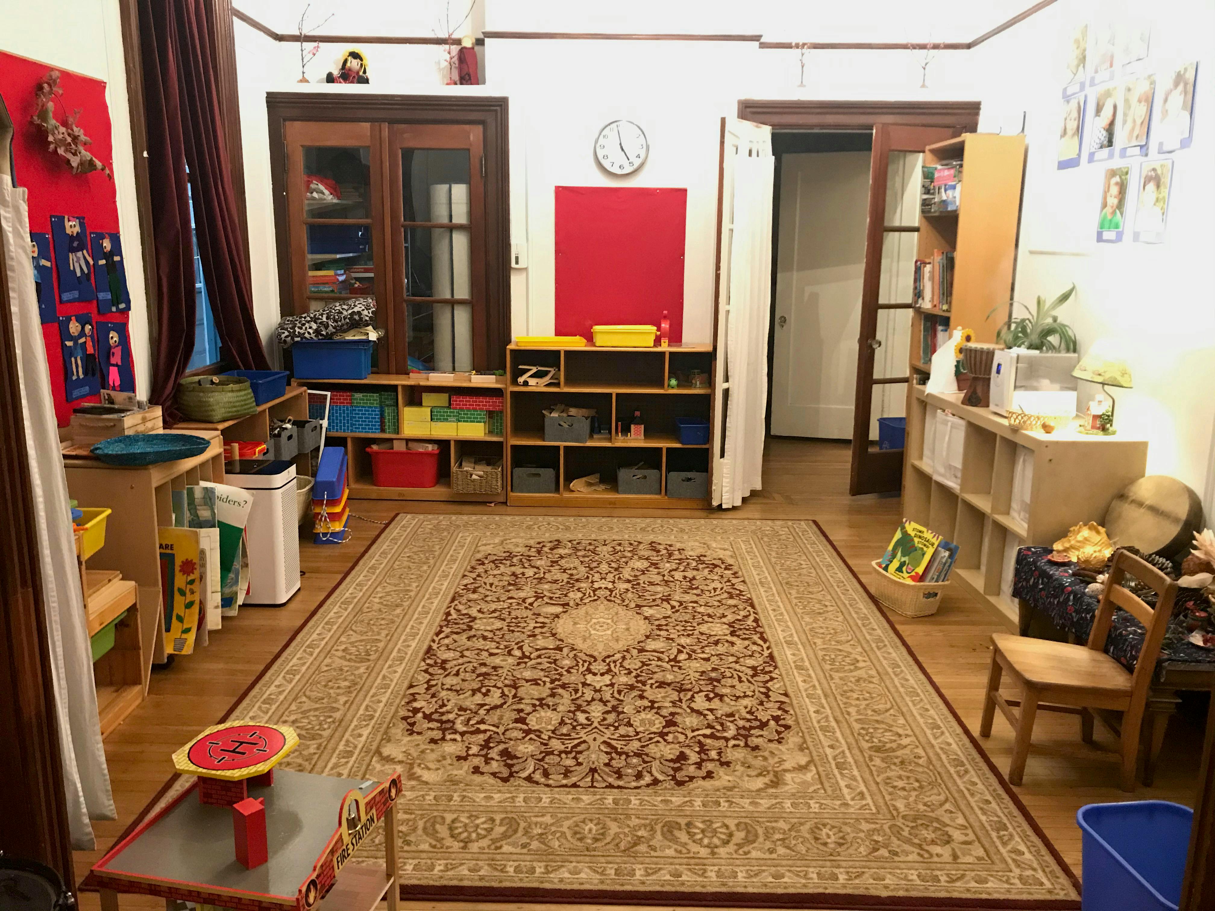 Classroom with shelves of toys and books, red carpet, and child-size fire station