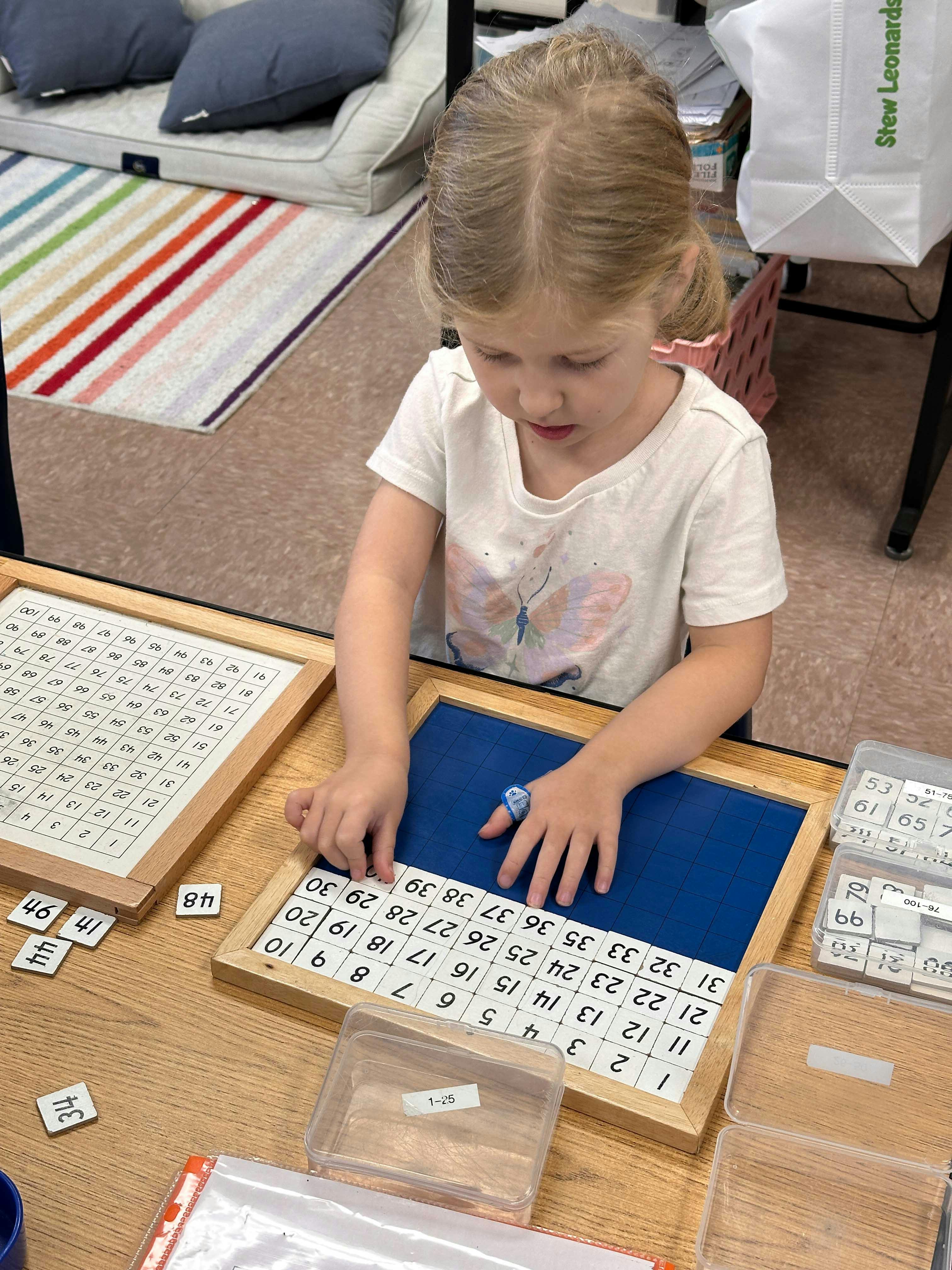 Child working with number tiles on a wooden board