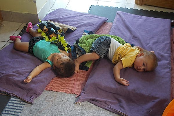 Two children lying on purple mats