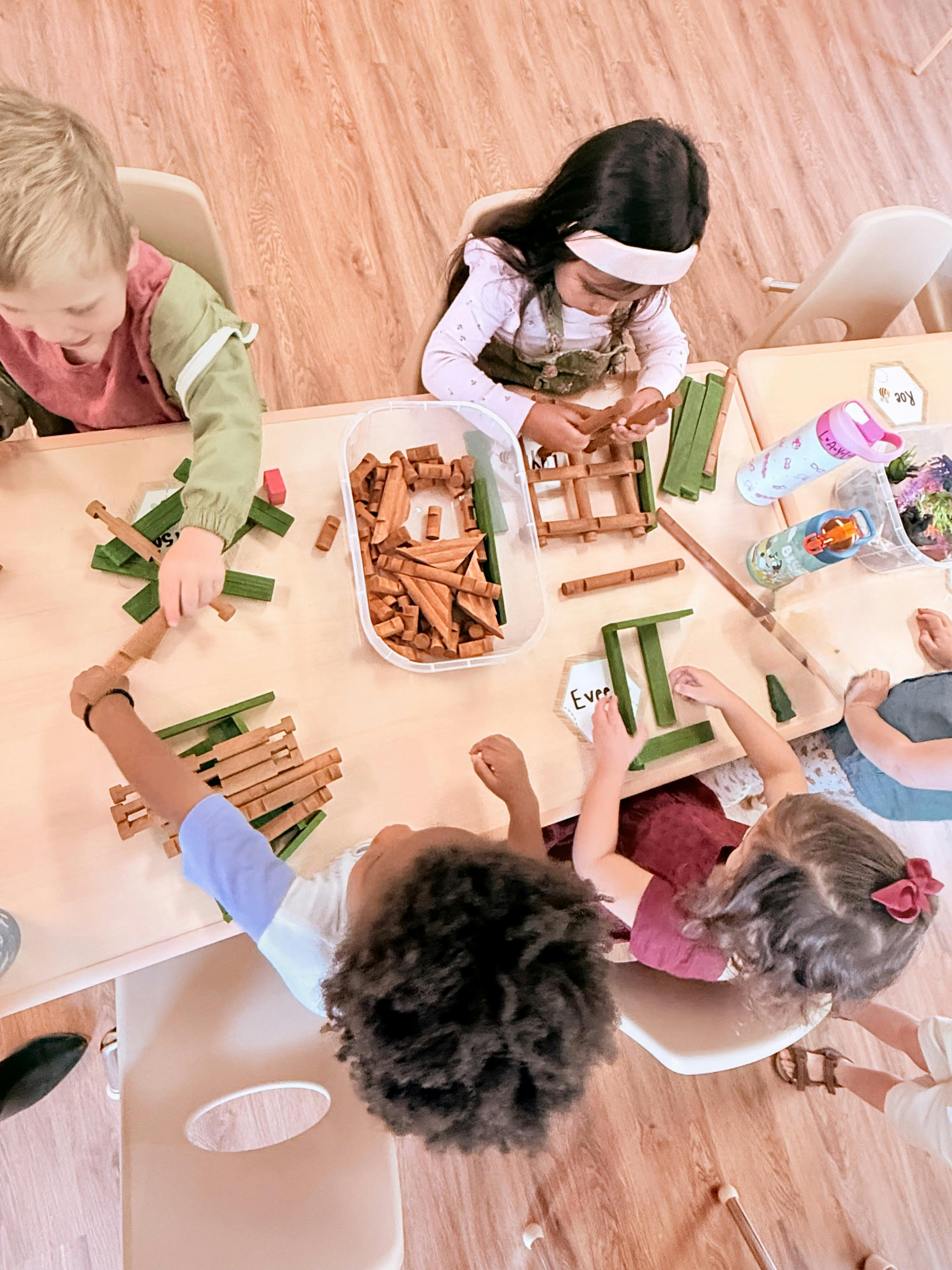 Children at a table playing with wooden and green building blocks