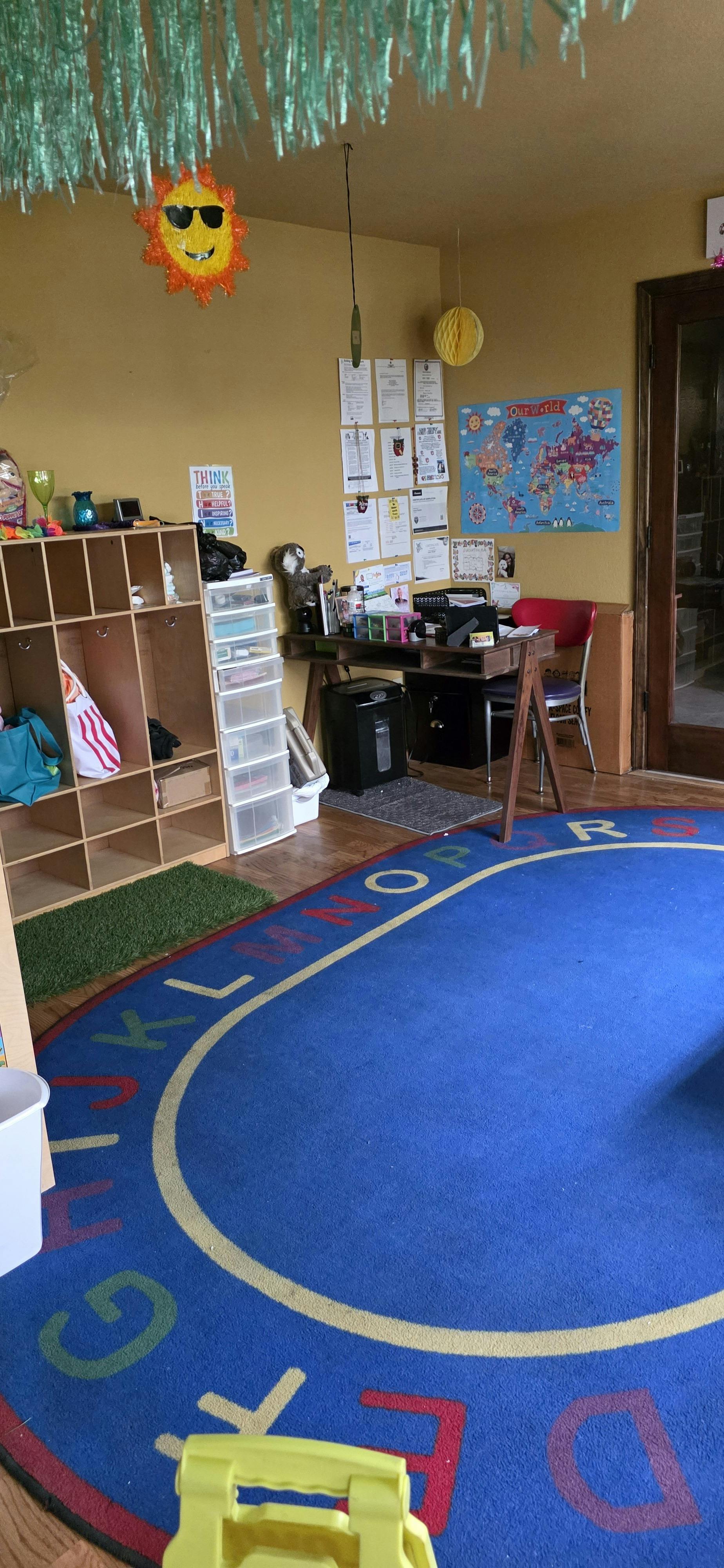 Classroom interior with alphabet rug, storage shelves, and desk
