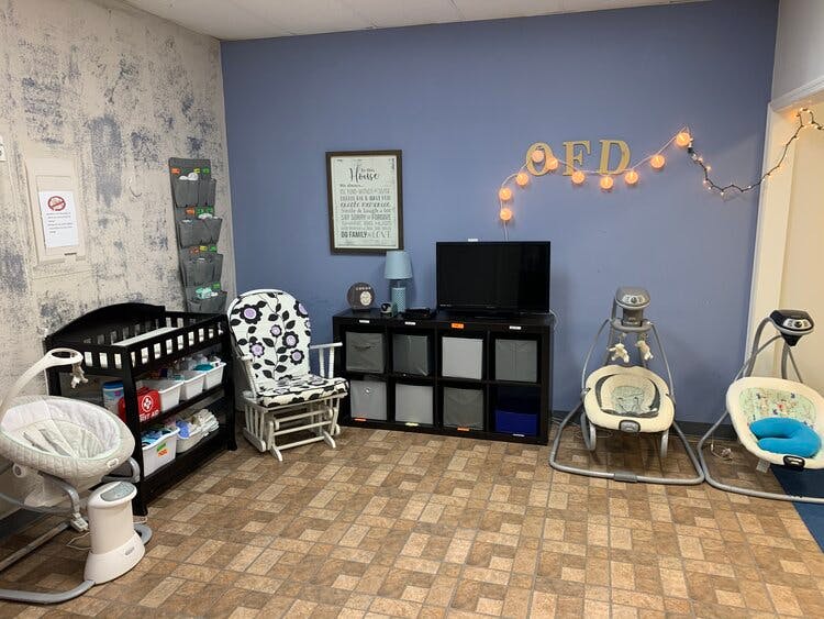 Nursery room with crib, rocking chair, and baby swings