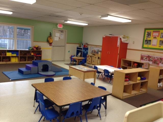 Children's classroom with tables, chairs, shelving, and soft play equipment