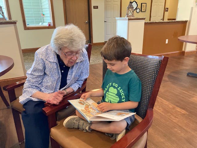 Adult and child sitting in chairs reading a book together