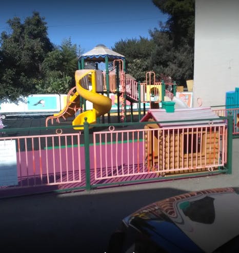Playground with slides and climbing structures behind a fence