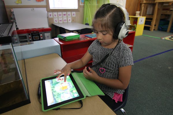 Child wearing headphones using a tablet in a classroom