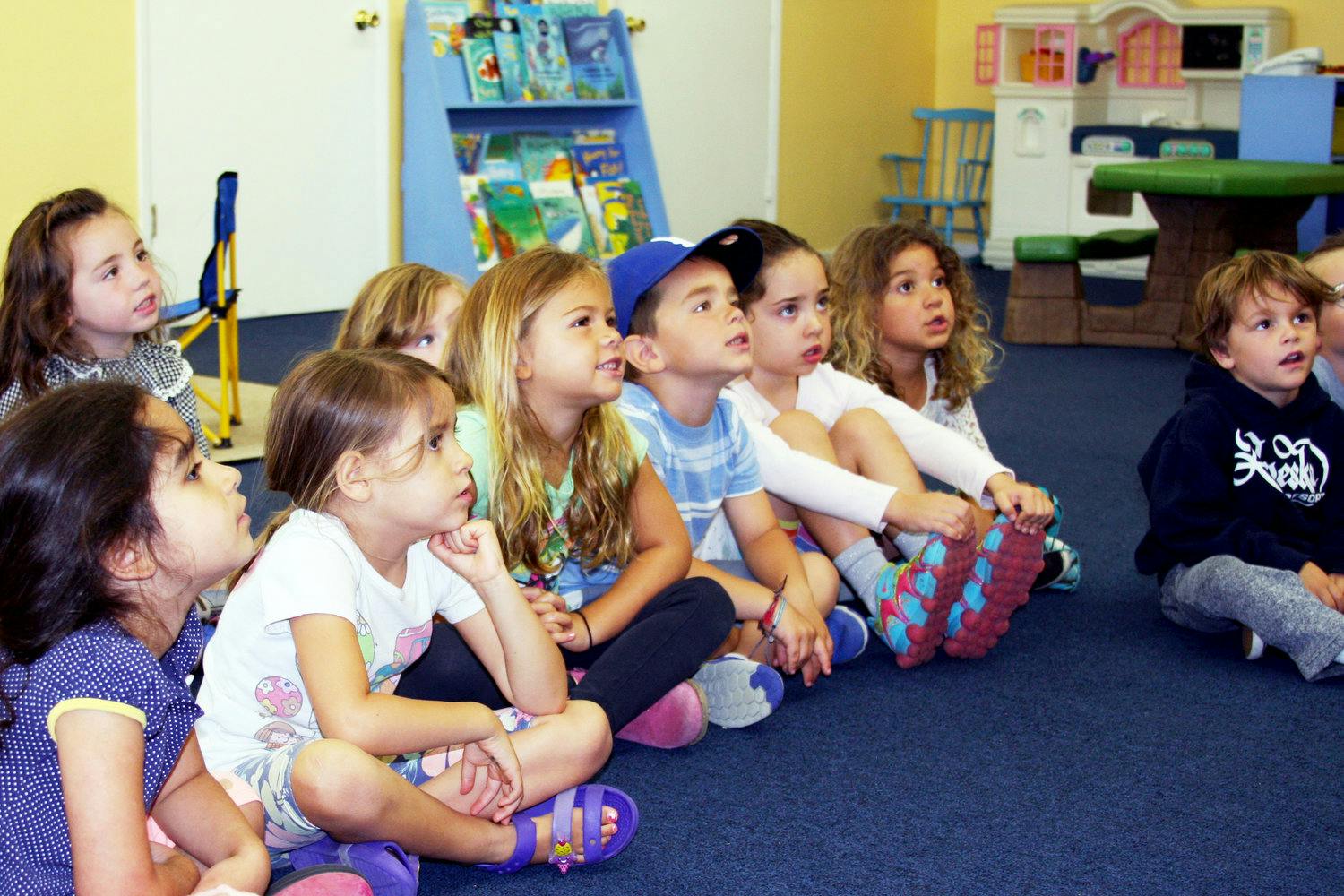 Group of children sitting on the floor looking up in a classroom