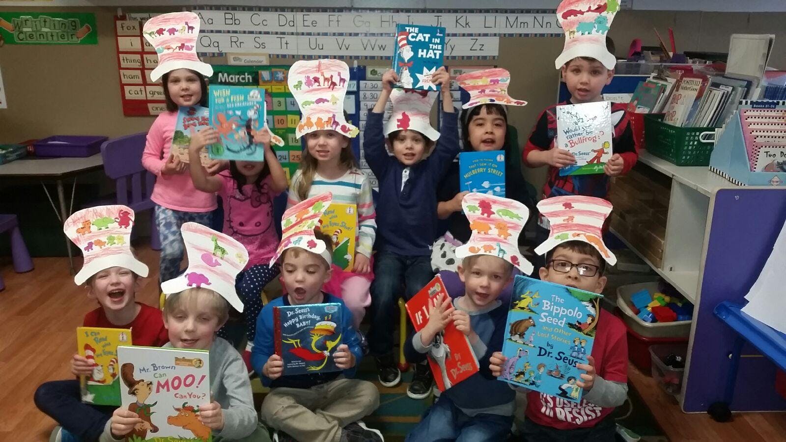 Children wearing paper hats and holding books in a classroom