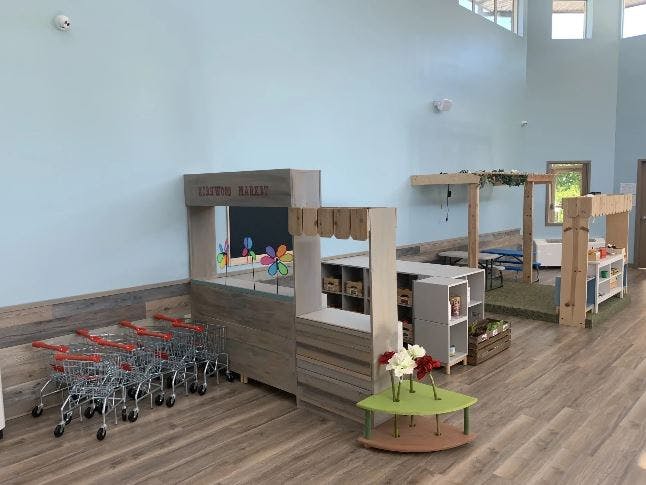 Play area with toy shopping carts and wooden market stalls