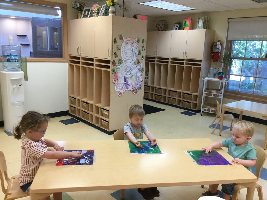Three children sitting at a table in a classroom