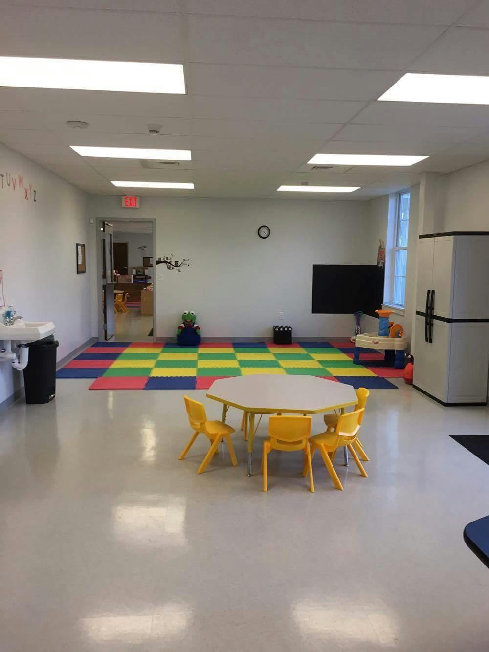 Classroom with colorful floor mats, small table, and chairs