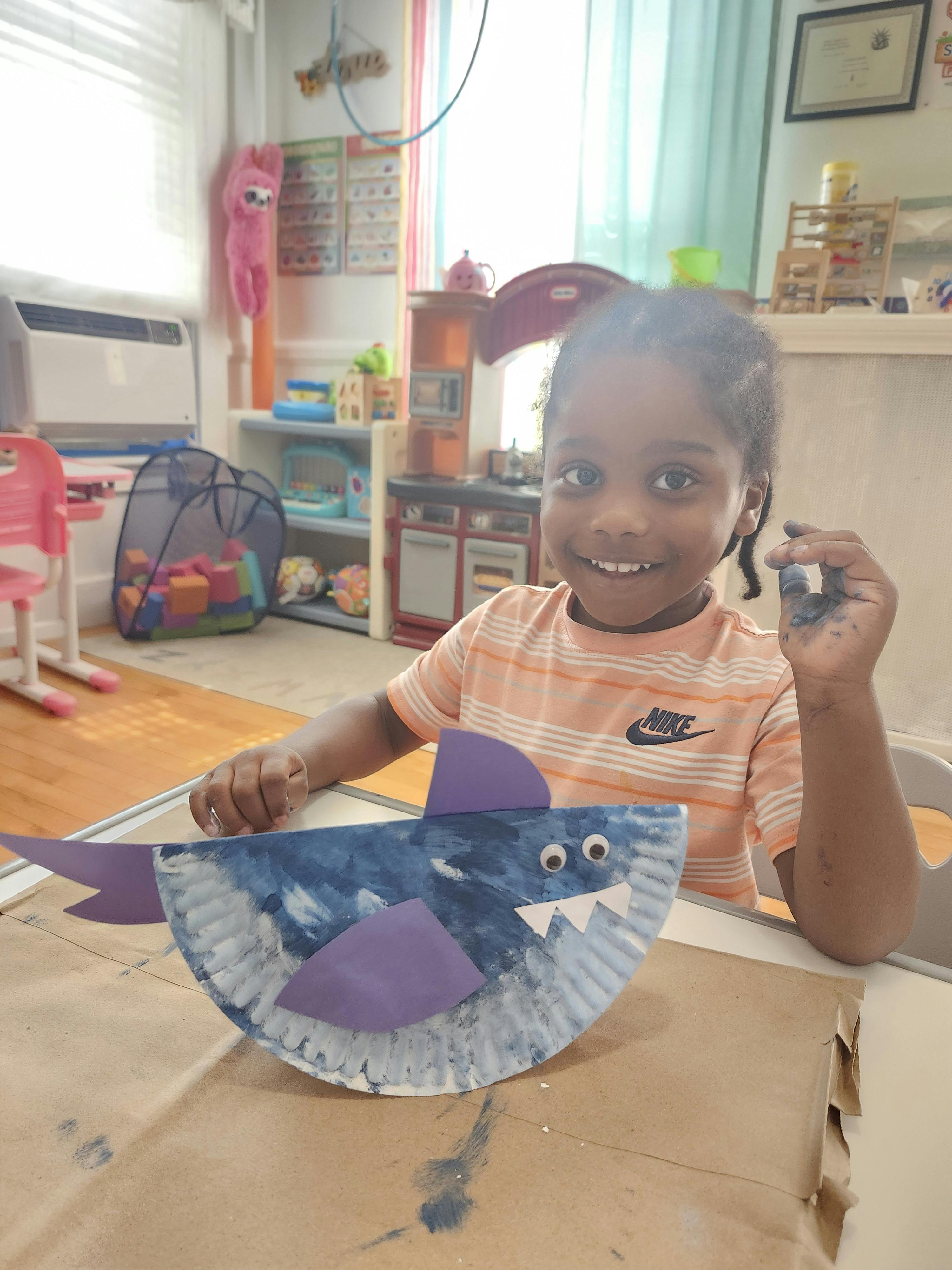 Child crafting a shark project from a paper plate